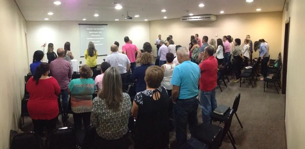 Culto de 2015 na sala do hotel, com a igreja de pé louvando